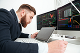 man studying crypto signal trade alerts on three computer screens