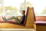 A man reclining back while typing on a laptop.