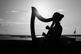 Silhouette of a woman playing a folk harp