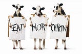 A common Chick-fil-A marketing image, showing three cows on their hind legs, holding signs that say, from left to right, “EAT”, “MOR”, and “CHIKIN”.