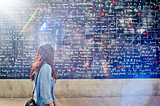 A woman looking at the Wall of Love located in Paris, France.