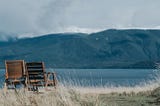 Two chairs, side by side, looking out onto a lake  … a metaphor for the therapeutic alliance.