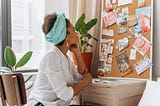 Woman in white top looking at a corkboard