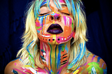 Gabbie Hanna with color paint and make-up all over her face, hair, and shoulders.