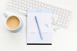 A light blue to-do list with a pen, keyboard and coffee mug