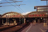 Wroclaw train station. A man walking along the platform. Overhead wires.