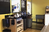 diner coffee station behind serving counter, blackboard menu backsplash