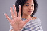 Woman holding up her hand indicating — stop — please listen and do not hurt me