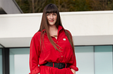 Laurens wears a red boiler suit in front of a beautiful whitebuilding