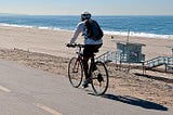 Los Angeles bike rider going down a road near the sandy Dockweiler State Beach