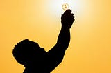 A man holding a light bulb up in the air.
