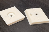 Photo showing a failed print of the revised mount on the left and a good one on the right (both printed with white PLA).