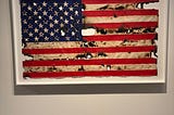 An acrylic painting of the American flag, framed, with dis-coloured lines and simulated burn marks.