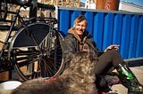 homeless man sitting on curb with bicycle and dog