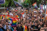 Demonstrators waving rainbow flags and smiling