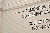 “Tomorrow is a different day. Collection 1980 to Now.” on a white, brick wall.