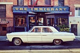 A classic car parked in front of the Immigrant wine and beer bar