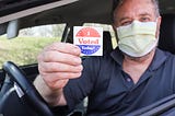 Man with mask holding “I Voted Today” Sticker