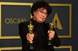 Bong Joon Ho holding two of his four Oscars