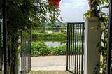 Open gates of a house in vietnam with a view of water and greenery