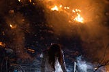 Burning world and woman in white shirt on knees rising up.