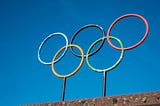 Photograph of the Olympic rings against a clear blue sky.