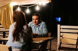 Man and woman sitting at a table in the evening on a first date.