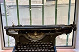 Antique typewriter in a barred window looking onto a street