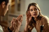 Young displeased woman ignoring her boyfriend who is begging for forgiveness