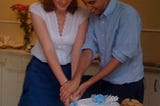 A couple cutting a wedding cake.
