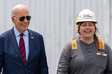 Joe Biden, in his aviator sunglasses, standing with a construction worker.