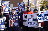 Several ATU members holding signs that say “We are one ATU” and “ATU on strike.”