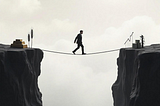 Man walks a tightrope between gold, wheat, and oil on one side and profits on the other — symbolising risk in commodity trading.