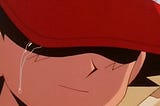 Ash, the original main character from the Pokemon series, sheds a single tear, his eyes hidden behind his red cap and a slight smile on his face