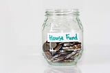 glass mason jar filled with coins and note that says house find, buying your first house