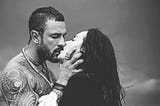 Tattooed man passionately kissing a dark haired woman — Picture from Depositphotos.com
