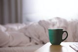 Hot steaming coffee cup on nightstand