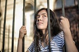 Young woman trapped behind prison bars