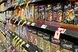 Boxes of breakfast cereal on the shelf of an aisle in a supermarket