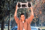 Image capture of iconic scene where actor John Cusack holds a boombox high over his head in the film ‘Say Anything.’