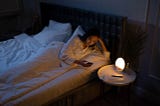 a girl lying on a bed using a mobile phone instead of sleeping