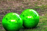 A pair of glowing green balls on the ground in a park