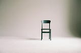 An empty chair stands in the middle of an empty room.