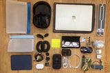 Tech gear arranged on wood floor. Many electrical gadgets including a laptop and headphones.