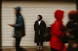 Image of a Muslim woman waiting on a busy streetscape.