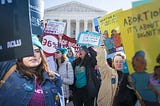 Pro-choice women holding signs in front of the Supreme Court building.