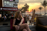 Image of Author sitting on a restaurant patio with the sunset in the background.