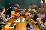 Picture of a squad working together on a bug bash ceremony. There are eight focused people seated around a rectangular table