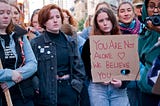 A group of students gathers to speak up for sexual violence survivors. One student is holding a sign that reads ‘You are not alone. We believe you.”