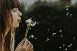 Pretty girl blowing on a Dandelion